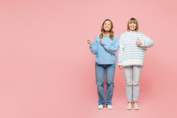 Full body elder parent mom with young adult daughter two women together wearing blue casual clothes point index finger aside on area isolated on plain pastel light pink background. Family day concept.