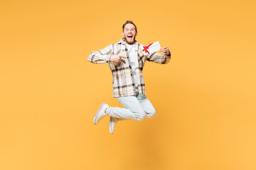 Fototapeta na wymiar Full body young surprised man he wearing brown shirt casual clothes jump high hold gift certificate coupon voucher card for store isolated on plain yellow orange background studio. Lifestyle concept.