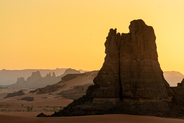 Landscape of the Red Tadrart in the Sahara Desert, Algeria. Sunset behind wind-sculpted sandstone...