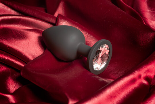 silicone butt plug with crystal on burgundy satin fabric
