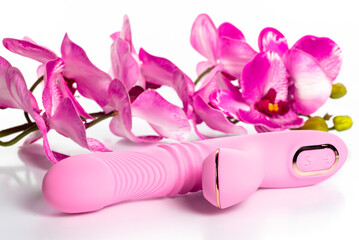 pink vibrator with an artificial branch of orchid flowers on a white background