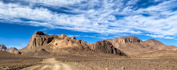 Hoggar landscape in the Sahara desert, Algeria. A view of the mountains and basalt organs that stand around the dirt road that leads to Assekrem. - 750082328