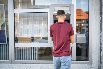 man teenage student using credit card and withdraw cash at the ATM