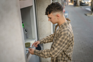 man teenage student using credit card and withdraw cash at the ATM