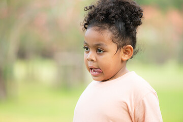 Happy young girl smiling in a green park during summer, portraying childhood joy and innocence