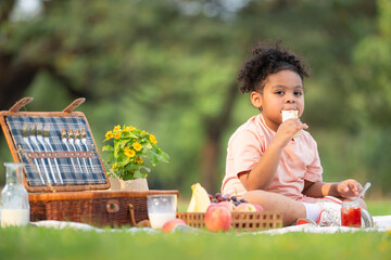 Happy family enjoying a picnic in the park, with kid eating jam bread, surrounded by nature
