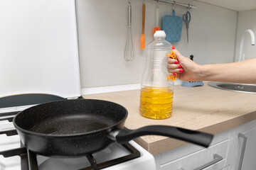 housewife pours sunflower oil into a frying pan.