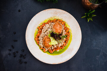 Chicken cutlet with barley porridge, beans and greens on dark background.