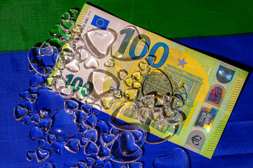 100 dollar bill on Ukrainian flag with glass hearts.