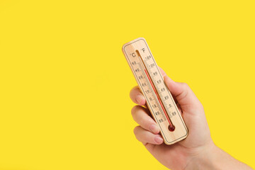 Hand with Outdoor Thermometer on Yellow. Reflects scorching heat, great for summer safety tips or...