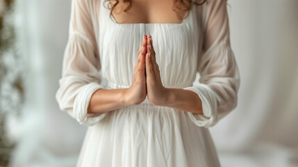front view close up of a woman's hands together, praying devout, wearing pure white dress, Meditating. 