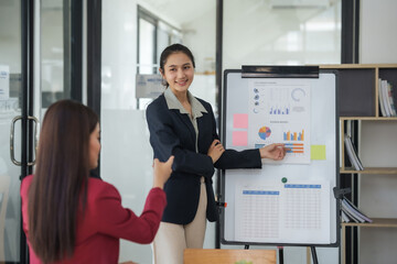Young professional young asian businesswoman confidently presenting charts and graphs during a...