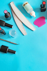 A set of tools for manicure: a set of gel polish, a nail file, a pusher, acetone, a stamp on a delicate blue-pink background. Top view. Place for text