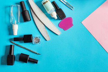 A set of different tools for removing manicure and gel polish on a blue background. Several files, brushes, a pusher, and a degreaser. Place for text. - obrazy, fototapety, plakaty