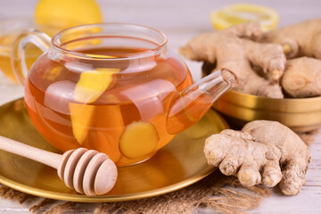 Ginger tea with lemon and honey in a small glass teapot.
