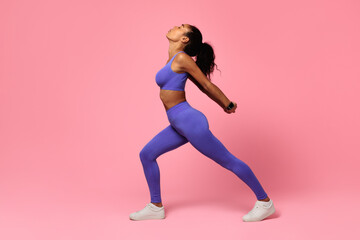 black woman in fitwear performing backbend in lunge position, studio