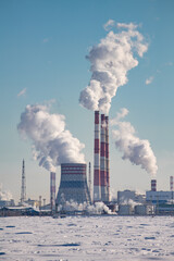 Termal power plant. Combined cycle gas turbine power plant. Large steaming hyperboloid cooling tower and smoking chimneys