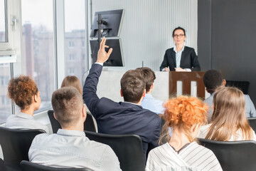 Businessman raising hand at seminar, having question to speaker
