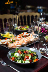Dinner Greek salad of fresh cucumber, tomato, sweet pepper, lettuce,feta cheese, olives and balsamic vinegar with bruschetta on table.