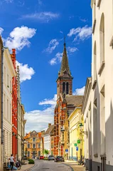 Fotobehang Brugge city historical centre, empty narrow street road in Bruges old town Burg quarter district, Izvorul Vietii Brugge church Gothic architecture style tower, West Flanders province, Belgium © Aliaksandr