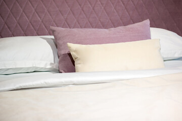 Soft pillows on a large bed in pastel colors