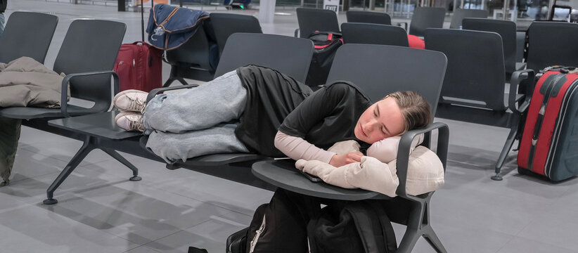 Travel, airport, woman waiting for a flight sleeps on a seat at the airport, solo travel, airport transit area, travel experiences, authentic travel