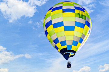Colorful hot air balloon flying over blue sky with white clouds	