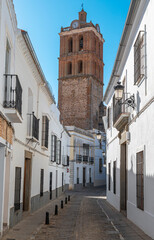 Fototapeta na wymiar Una calle peatonal de casas blancas en la villa española de Zafra con el campanario de la parroquia de la Candelaria, España
