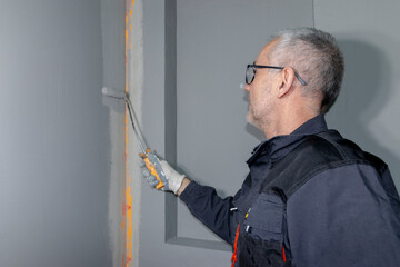 A builder worker applying waterproofing paint to the bathroom wall and floor. Applying...