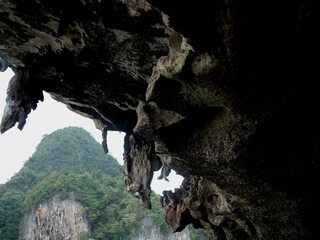 Cave over the water of limestone rock islet at Phuket Bay Thailand