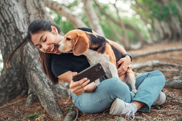 Selfie portrait of young asian woman with her beagle dog, in the park in summer. Adorable pet...