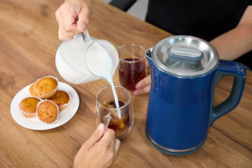 Man pours cream into cups of milk on the table