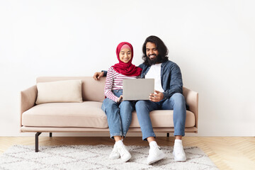 Portrait Of Romantic Muslim Spouses Relaxing With Laptop At Home