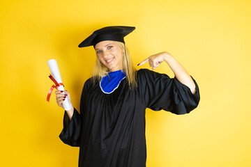Beautiful blonde young woman wearing graduation cap and ceremony robe looking confident with smile...