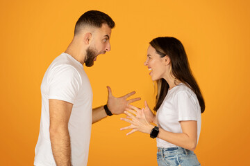 Animated young couple in a lively discussion, gesturing with their hands, both wearing white t-shirts