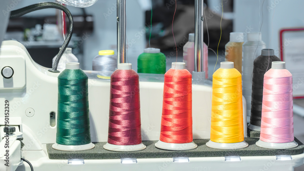 Aufkleber spools of color threads closeup, spinning machine