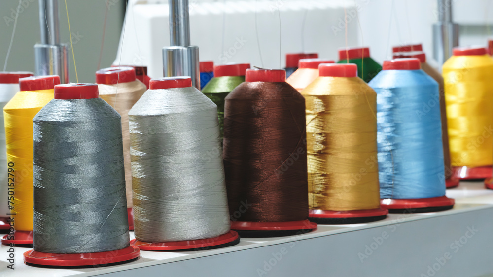 Poster Spools of color threads closeup, spinning machine