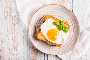 Close up of croque madame sandwich with ham, cheese and egg on a plate on the table top view