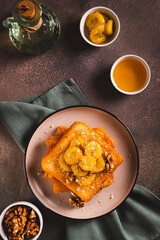 Caramelized bananas with nuts on fried bread on a dessert plate on the table top and vertical view