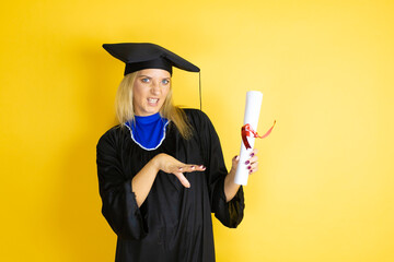 Beautiful blonde young woman wearing graduation cap and ceremony robe afraid and terrified with fear expression stop gesture with hands, shouting in shock. Panic concept.