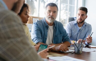 Beautiful business people are using gadgets, talking and smiling during the conference in office