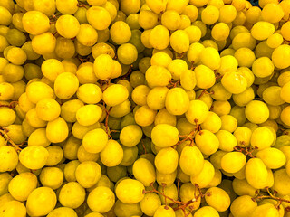 yellow grapes in boxes on supermarket counter, bunches of grapes lie in bulk.
