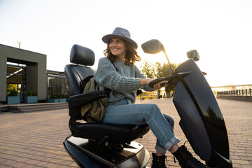 Woman tourist riding a four wheel mobility electric scooter on a city street