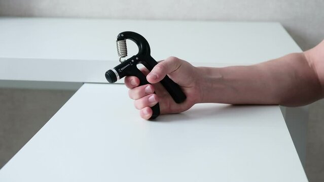 Physical therapy for the arm using an expander, a male hand close-up on a white background squeezes the expander. Recovery after a fracture.