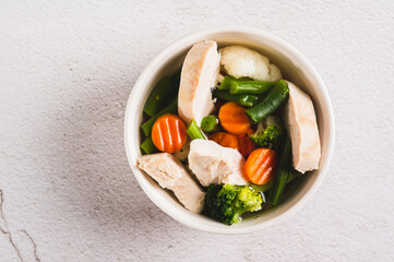 Close up of  soup with chicken, cauliflower, broccoli, carrots and green beans in a bowl top view