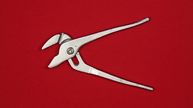 Adjustable steel wrench pliers. Tools in action on color background. Loopable stop motion animation. 4K top view. DIY video concept.