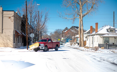 The red snowplow truck clearing fresh snow from street in a residential area