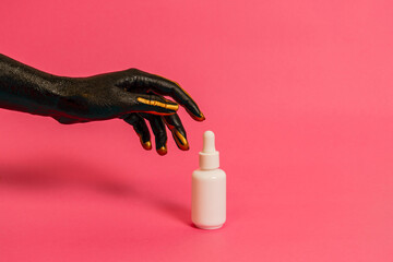 Black and gold painted elegant hand on skin with cosmetic unbranded bottle. Luxury, high fashion cosmetic products concept