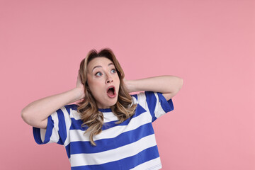 Portrait of surprised woman on pink background. Space for text