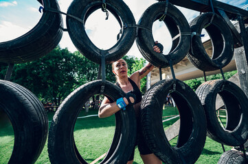 Woman passing a car tires wall during an obstacle course race outdoor